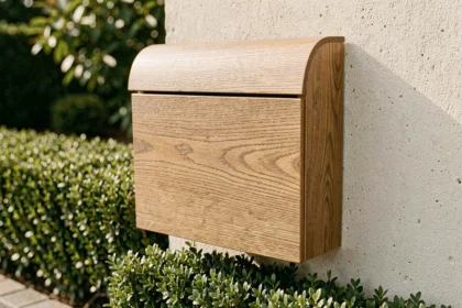 Boîte aux lettres habillée d'un film adhésif imitation bois sur mur en béton dans un jardin